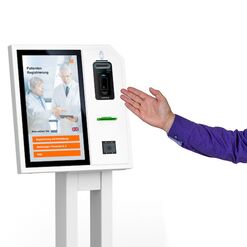 Berater zeigt auf self Service Patienten Terminal
